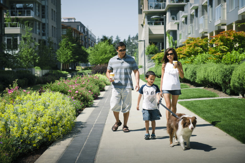 Family of three and a dog walking along a greenway in Wesbrook Village