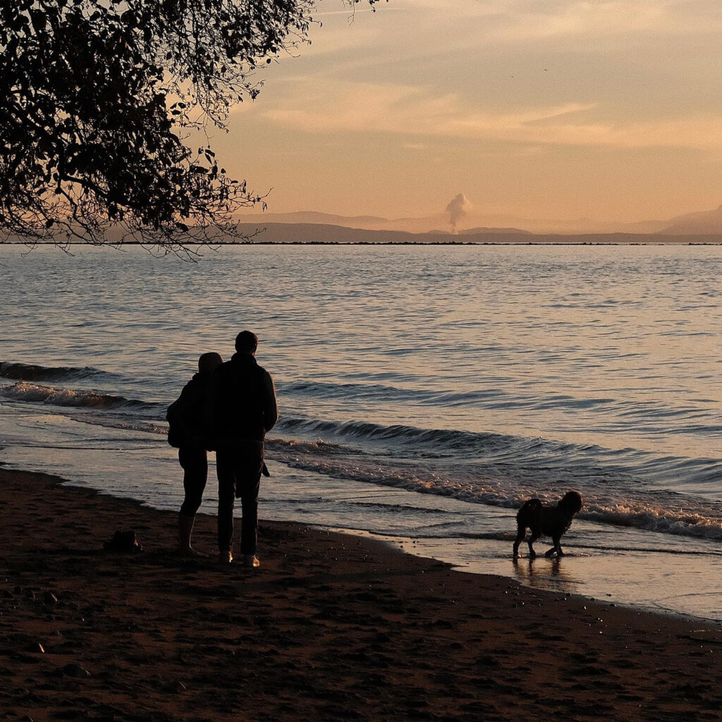 Wreck Beach sunset with 2 people and a dog.