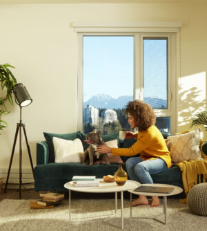 Woman in her living room on a couch with her dog.