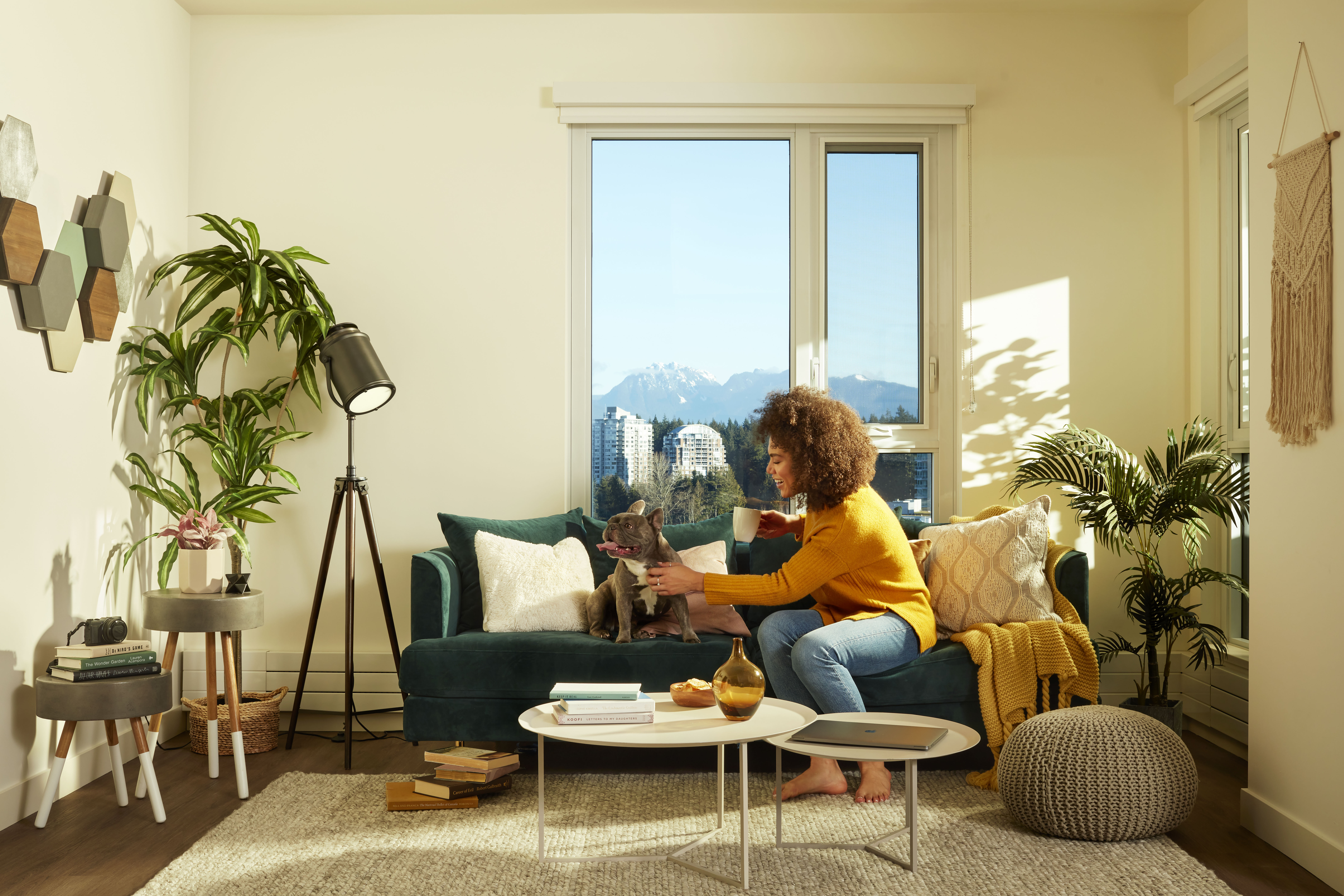 Woman in her living room on a couch with her dog.